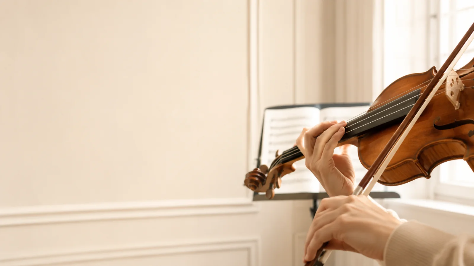 Dettaglio di mani che suonano un violino in una sala luminosa, corso di violino Accademia Ars Nova.